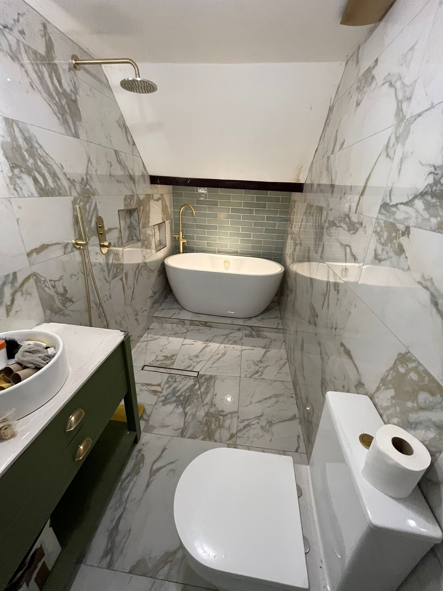 Full marble bathroom with green vanity and gold fixtures